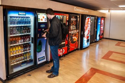 Man with backpacking buying drink from vending machine